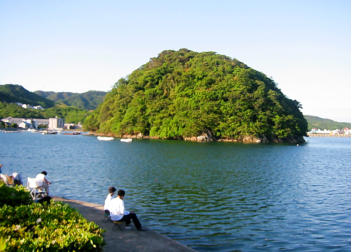 穏やかな入り江の海。青い海面にぽっかり浮かぶ丸い小さな緑の島、岸辺ではカップルや家族連れが釣り糸を垂れていて、ゆったりとした時間が流れているようです。