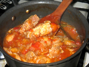 お鍋の中に赤い汁ものと、ローリエの葉っぱ、そして鶏肉の塊が顔を覗かせています。