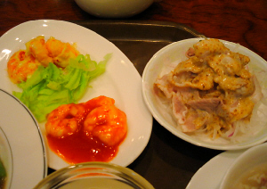 エビちりと、エビマヨの乗った、楕円形のお皿と、ゴマダレのかかったお肉、お肉の下には玉葱と大根の千切りが見えます。どちらも白い器です