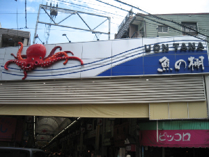 商店街のアーケードの入り口の看板。立体的なタコの姿と、魚の棚という漢字の上に、UONTANAとローマ字で書かれています。