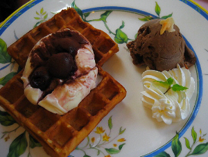 華やかな白地にブルーのラインのお皿、全体にブルーの花模様が。ワッフルが２枚、その上にアイスクリームと、カカオパウダーが、その隣にはチョコレートアイスクリームと、生クリームが並んでいます