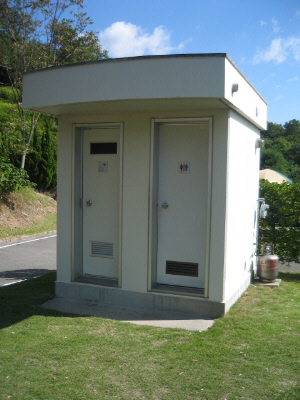 トイレとシャワールームの二つのドアが見える小さなコンクリート作りの棟。各区画に一個ずつ設置されています。勿論これのない区画もあります。