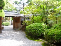 日本庭園風な入り口。入り口の屋根付きの門を入ると、玄関まで白い玉砂利が敷き詰められていて、植木の緑を一層引き立てています。