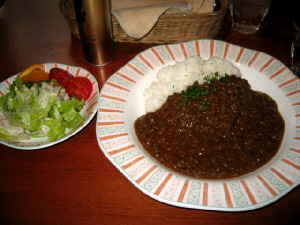 お揃いの大小のお皿に盛られたカレーとサラダ。ひき肉がたっぷりでお肉の粒がしっかり見えるカレーです。