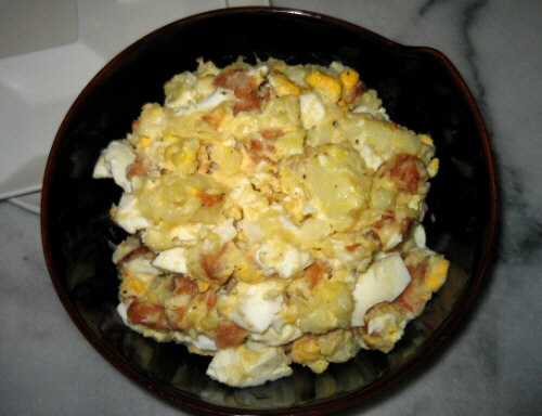 黒の大きめの器に入ったポテトサラダ。ゆで卵に、茶色いのは揚げられたサーモンのようで、それが角切りになってポテトと玉子の間に絡まっています。