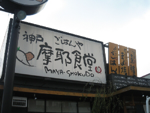神戸ごはんや「摩耶食堂」と大きく書かれた看板。大根とじゃが芋のイラストが可愛い。大きな看板の隣には、メニューが並んだ看板も。