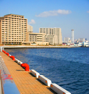 こちらも絵に描いたような入り江の川面。実際は海水ではないかと思われますが、真っ青で綺麗な水面です。ボートを繋ぐ係留杭がオレンジ色に塗られていて、水面の青に映えて綺麗です。向こう側にはビルや煙突が見えます。