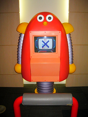 真っ赤なまん丸目玉のロボット。足は一本足です。胸に画面がついていて、どうやらクイズでも出しているようです。