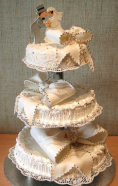 白いウェディングケーキ。白とシルバーのアラザンのみの装飾ですが、大きなリボンが可愛らしい3段のケーキ。上段には新郎新婦のモチーフが飾られてあります。