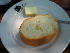 丸い白皿に取り分けたパン。お皿は淵に黒でレストランのシルエットが描かれたオリジナルなお皿です。