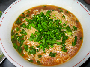 白いラーメン丼に入った味噌ラーメン。青ネギがたっぷりかかっています。