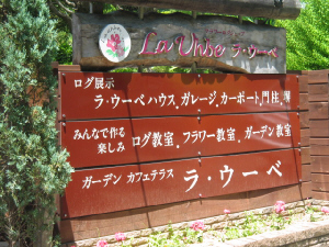 木製のフェンスに木の看板。ログ展示場も兼ねたカフェテラスがあります。