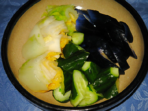 やや大きめの丸い器、縁取りが紺色の益子焼の器です。白菜・きゅうり・茄子の漬物が盛り込まれています。