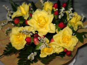 黄色いバラと真っ赤な木の実、白い小さな花がバランスよく盛り込まれたテーブルフラワー。