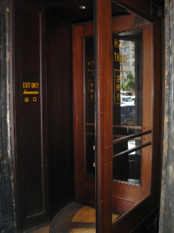 海外の古いホテルのような回転扉の入り口。回転扉はかなり大き目のもので、一つの区切りに大人が二人入っても、全く窮屈ではありません。かなり使い込まれたどっしりした回転扉です。昔ここは銀行でした。