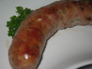 白いお皿にこんがり焼き色のついたソーセージ。パセリがアクセントに添えられてあります。